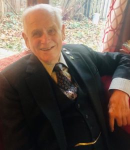 A man in a suit sitting on a red couch.