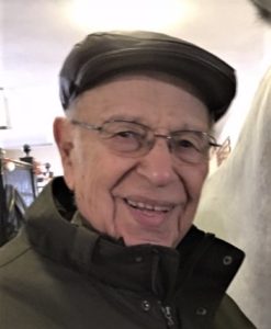 An older man smiling next to a white horse.