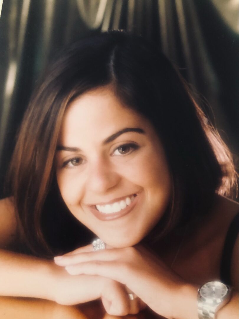 A young woman smiles while sitting at a table.