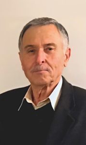 An older man in a black jacket and white shirt.
