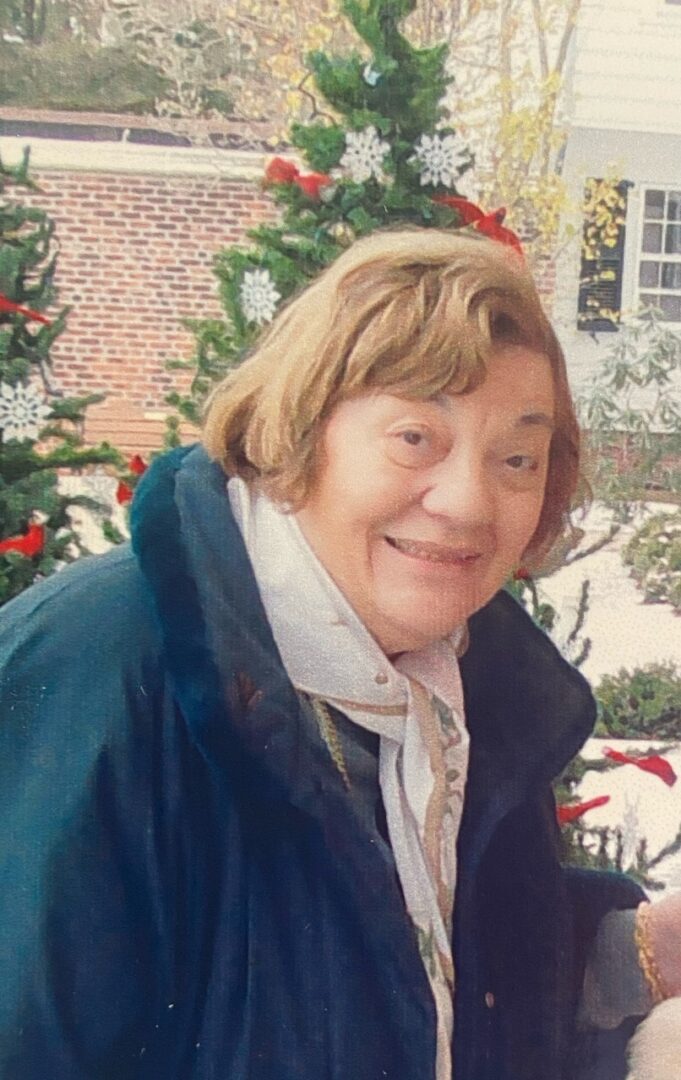 An older woman with a dog in front of a christmas tree.