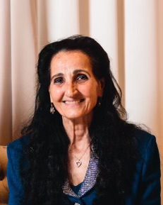 A woman in a blue suit sitting on a couch.