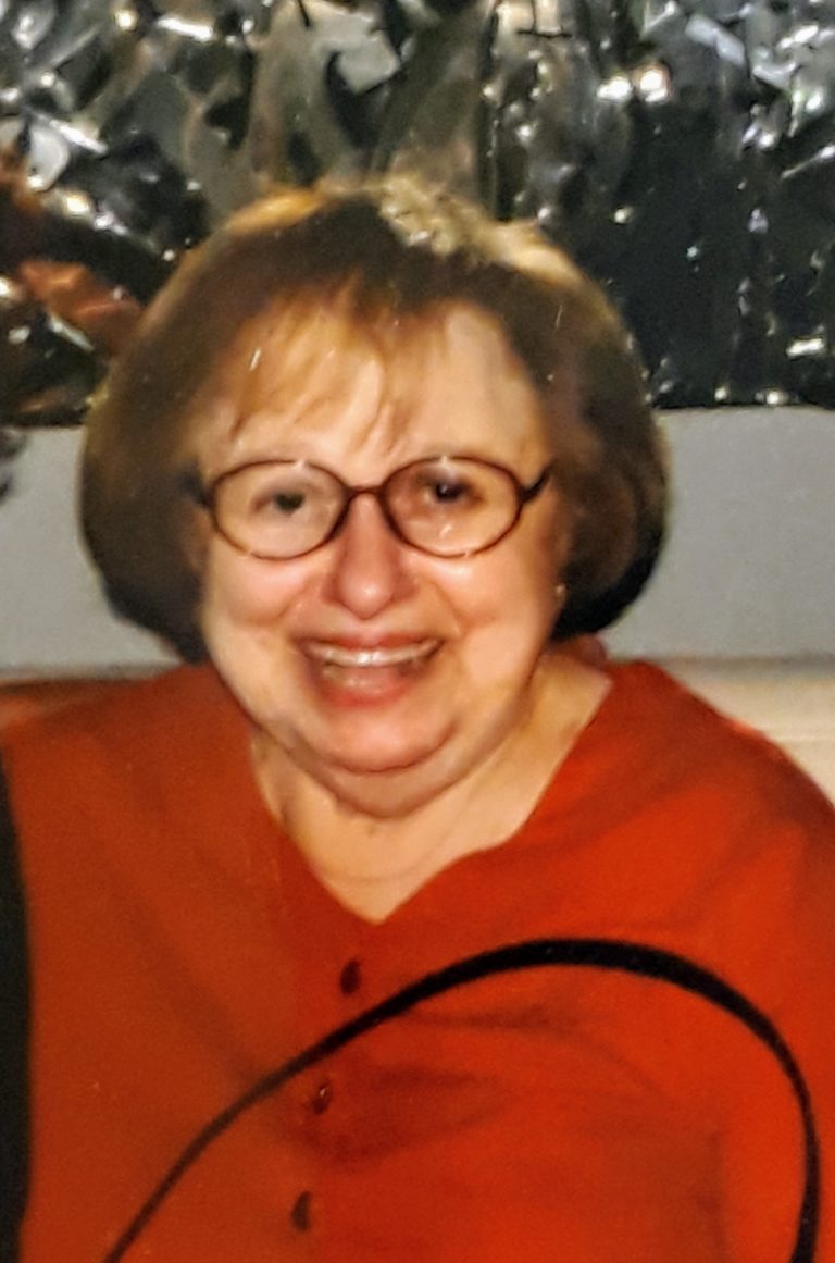 An older woman with glasses is smiling for the camera.