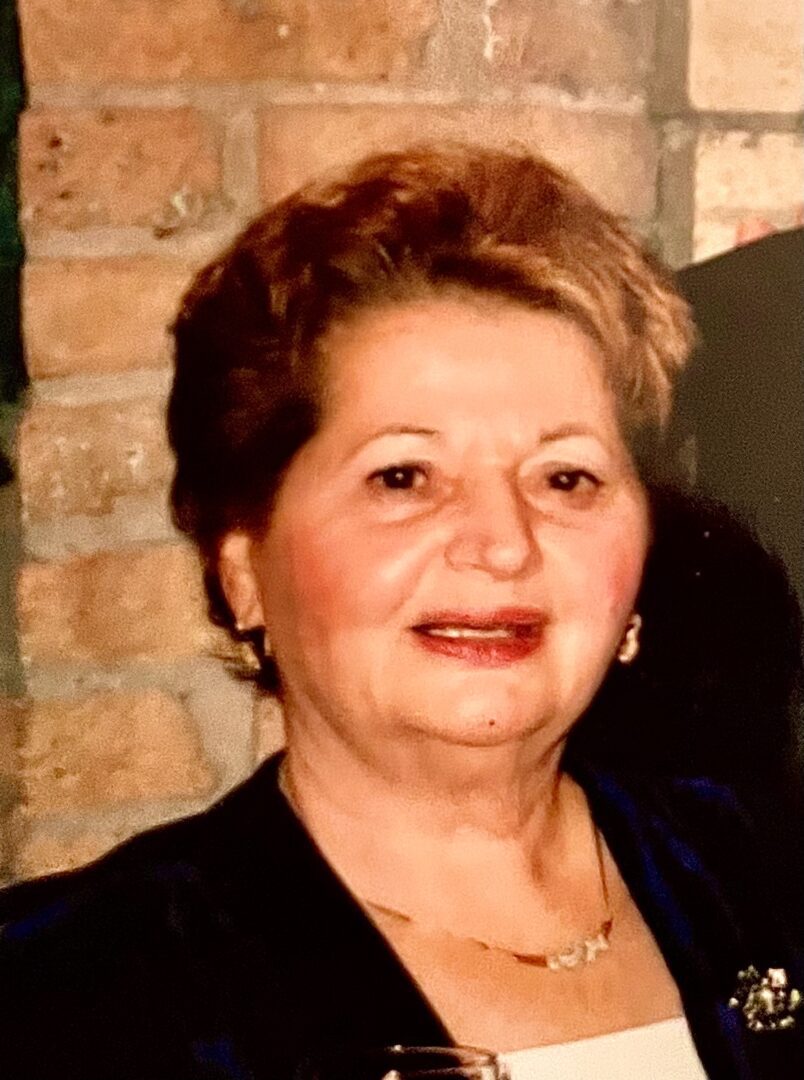 An older woman is holding a glass of wine.