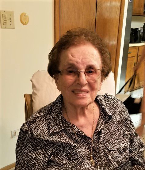 An older woman sitting in a chair and smiling.