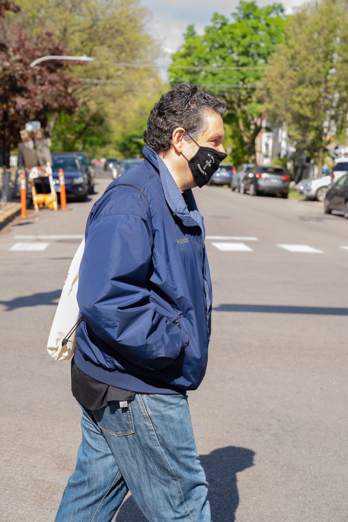 A man wearing a face mask crossing the street.