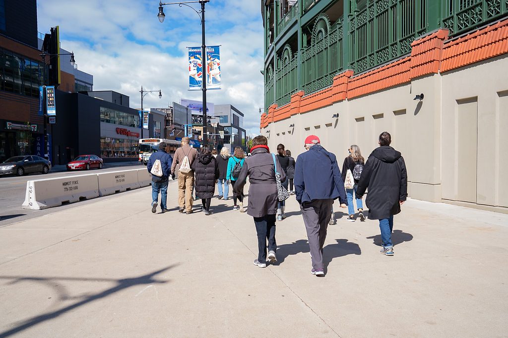 A group of people walking down a sidewalk in front of a building.