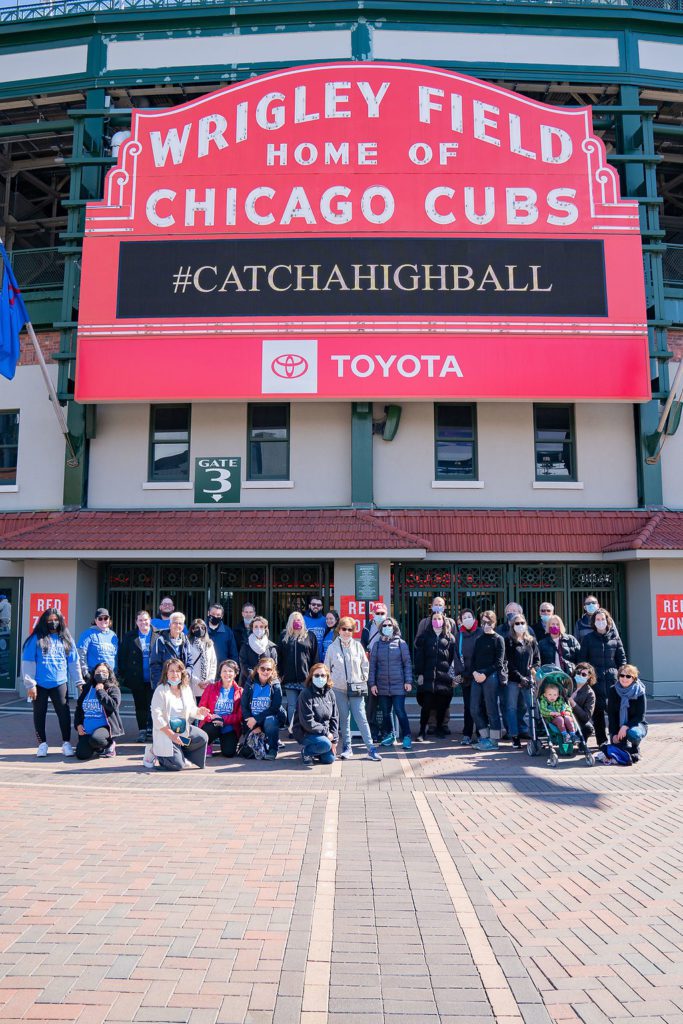 A group of people standing in front of the chicago cubs stadium.