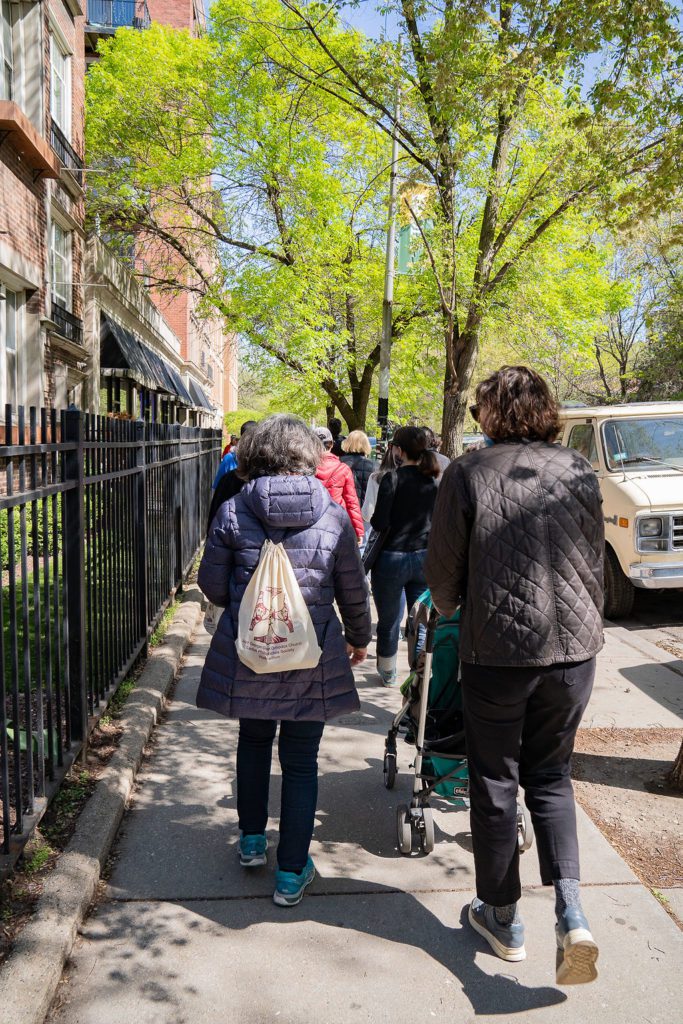 A group of people walking down a sidewalk.