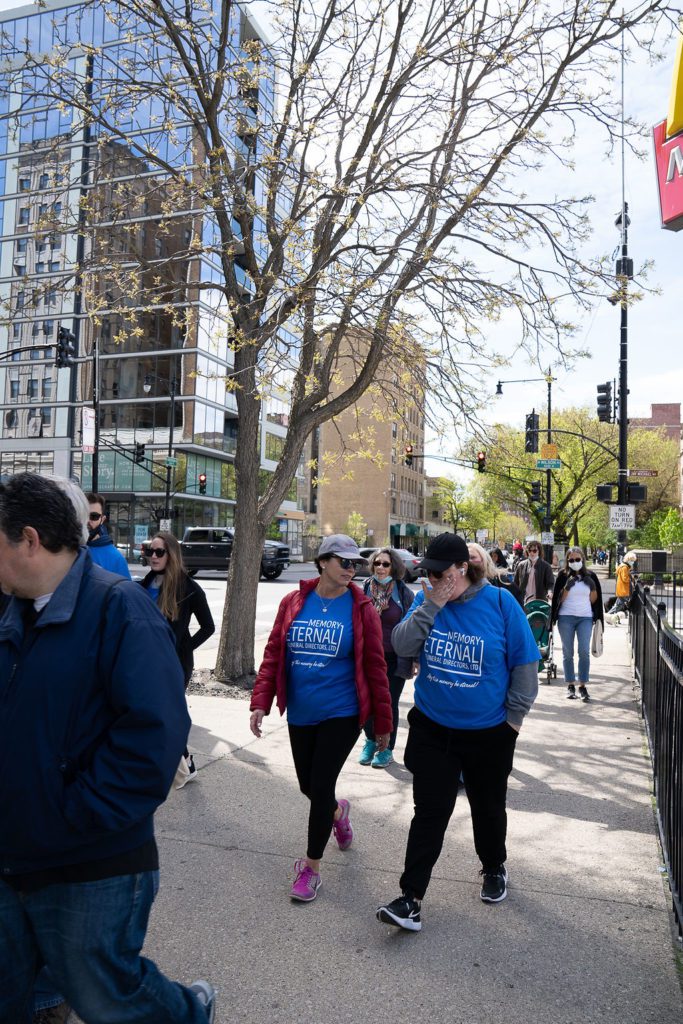 A group of people walking down a sidewalk with a mcdonald's sign.