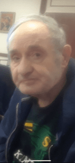 An older man is sitting in a chair.