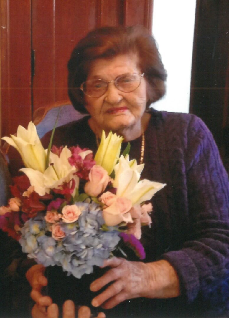 An older woman holding a bouquet of flowers.