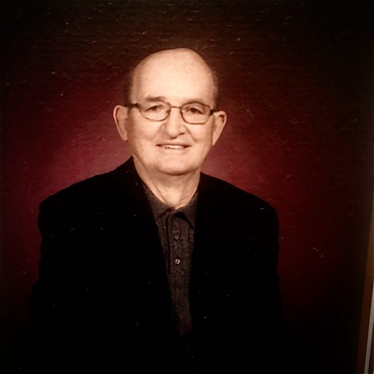 An older man in glasses is smiling for the camera.
