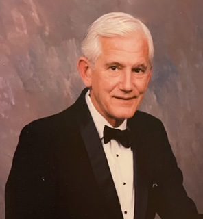 An older man in a tuxedo posing for a photo.