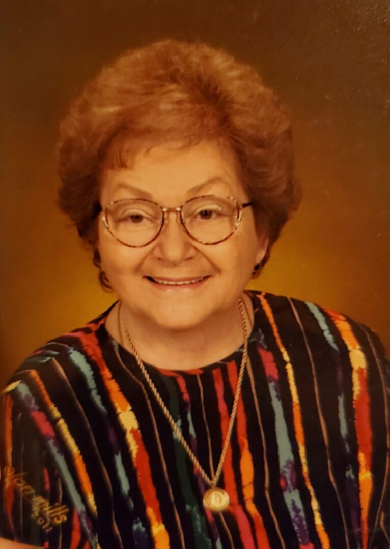 An older woman wearing glasses and a colorful top.