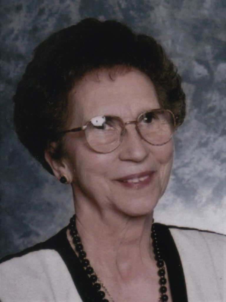 An older woman wearing glasses and a necklace.