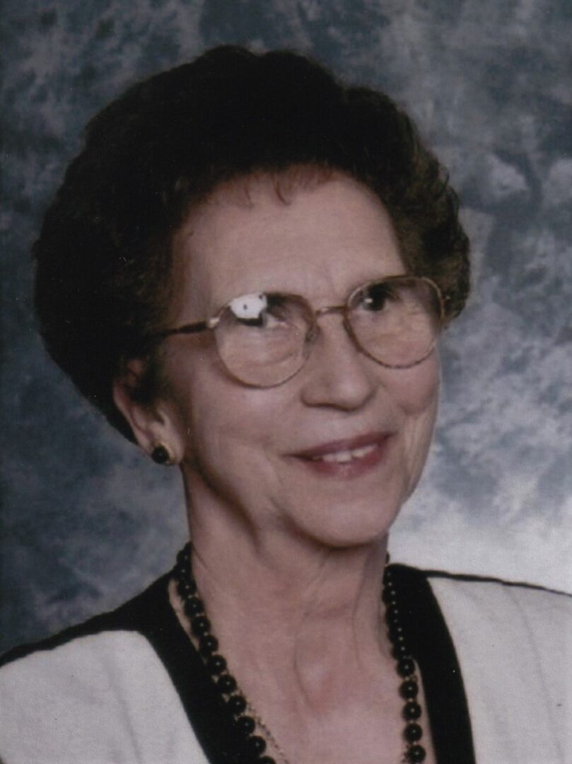 An older woman wearing glasses and a necklace.