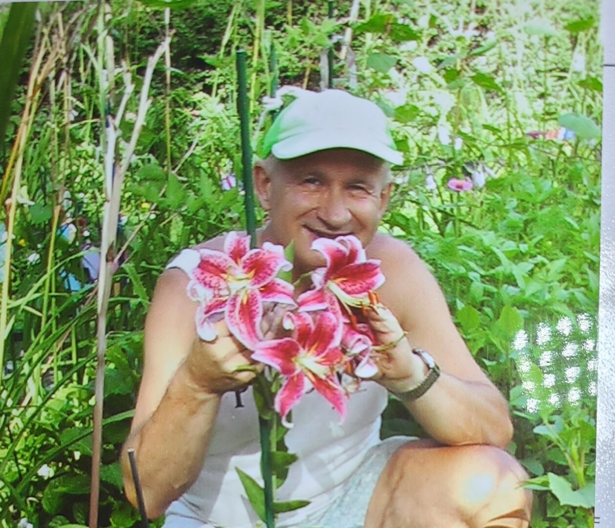 A man crouching down with a flower in his hand.
