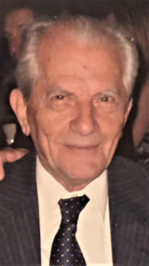 An older man in a suit and tie is posing for a photo.