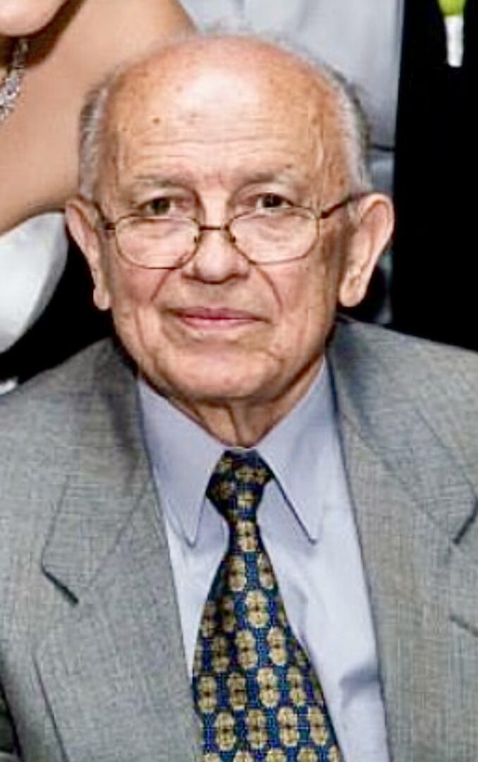 An older man in a suit and tie posing for a photo.