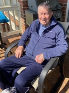 An older man sitting in a chair on a porch.
