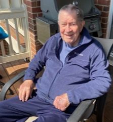 An older man sitting in a chair on a porch.