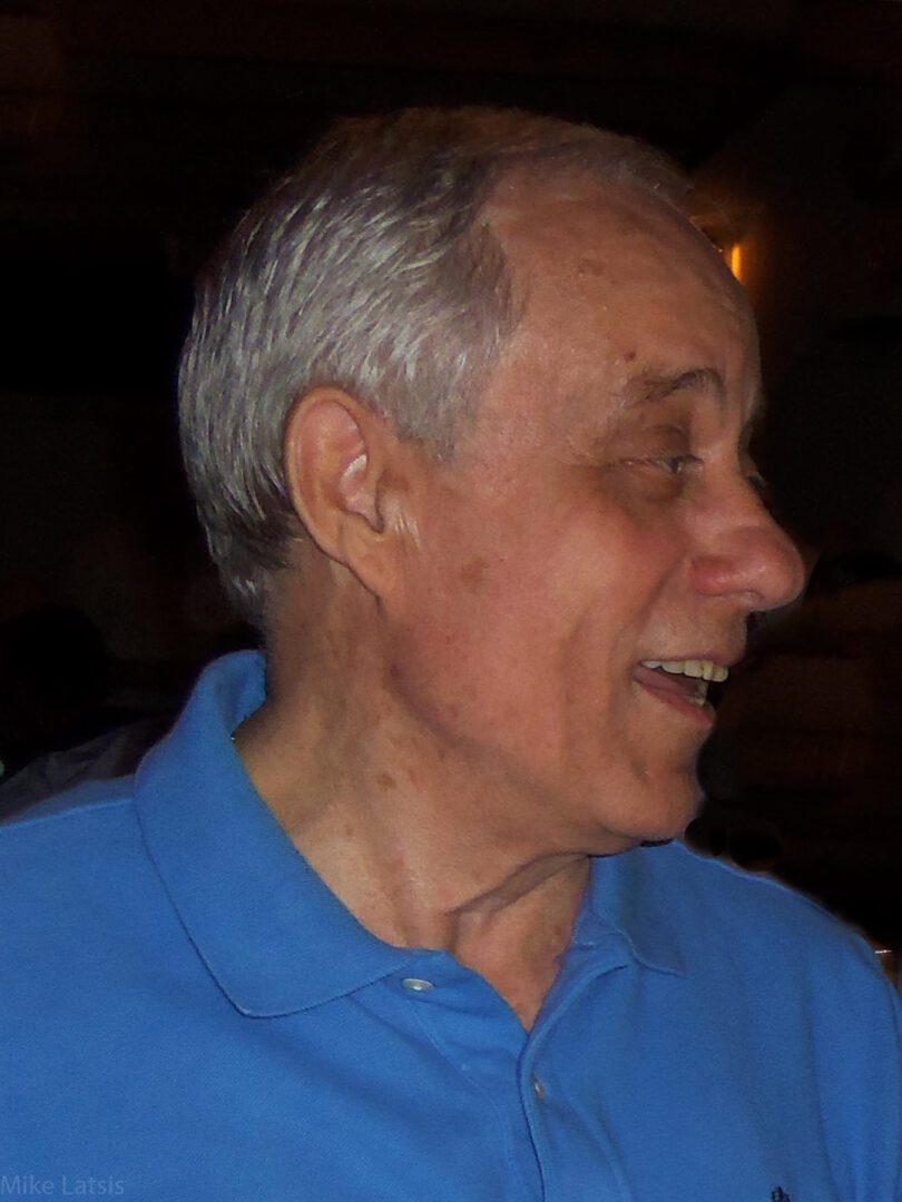 An older man smiling in a blue shirt.