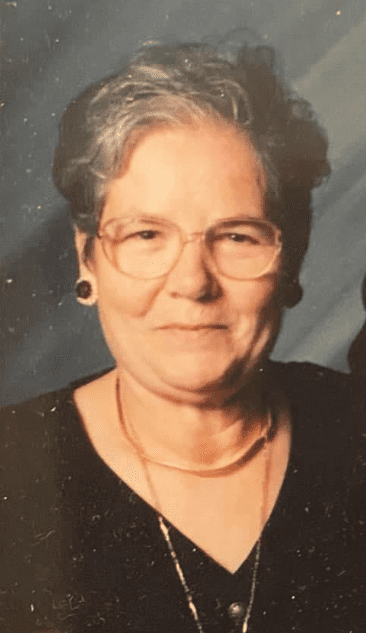 An older woman with glasses is posing for a photo.
