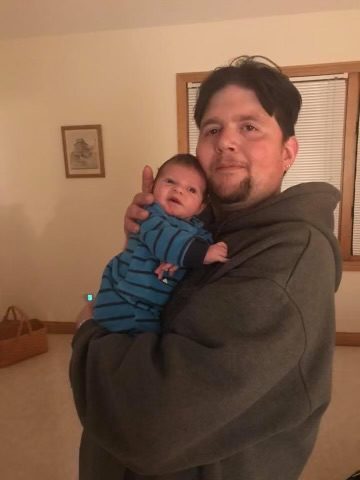 A man holding a baby in a living room.