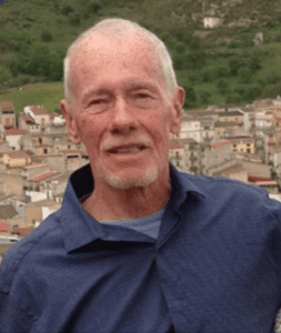 An older man standing in front of a town.