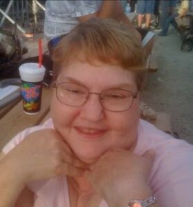 A woman wearing glasses and a pink shirt at a concert.