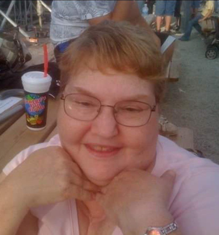 A woman wearing glasses and a pink shirt at a concert.