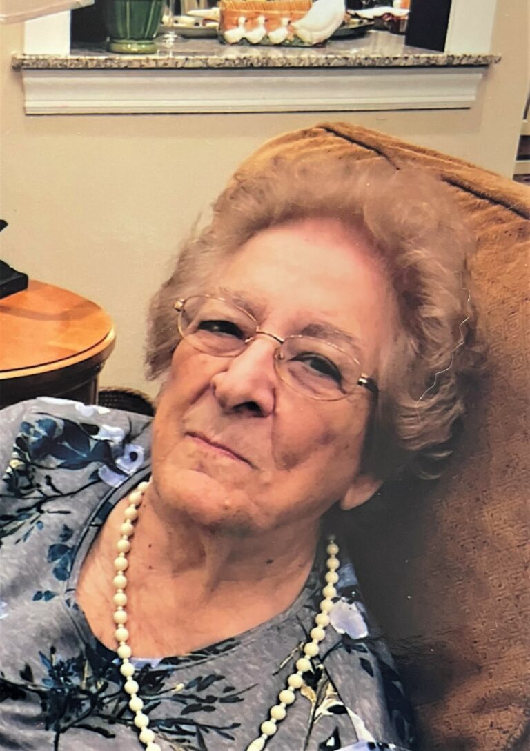 An older woman sitting in a chair with glasses.