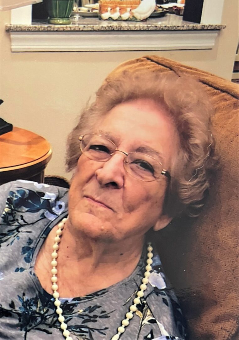 An older woman sitting in a chair with glasses.