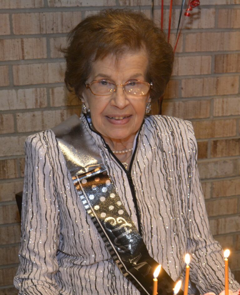 A woman sitting in front of a birthday cake.