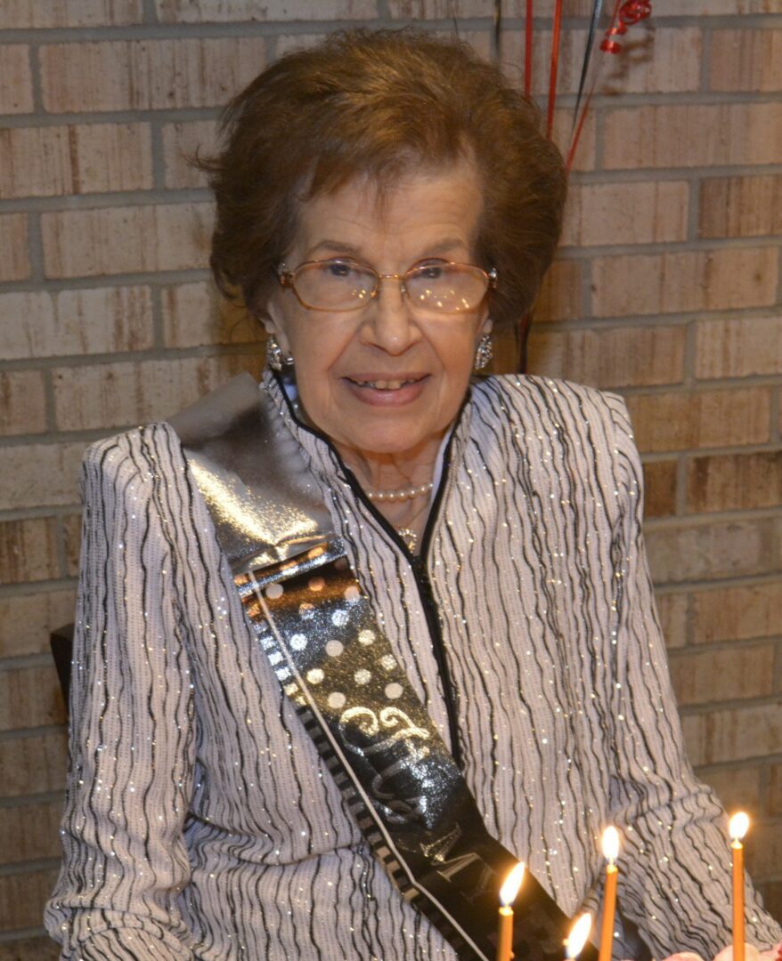 A woman sitting in front of a birthday cake.