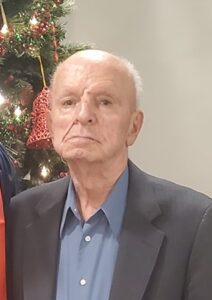 Two older men standing in front of a christmas tree.