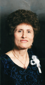 Woman in a blue floral dress smiling.