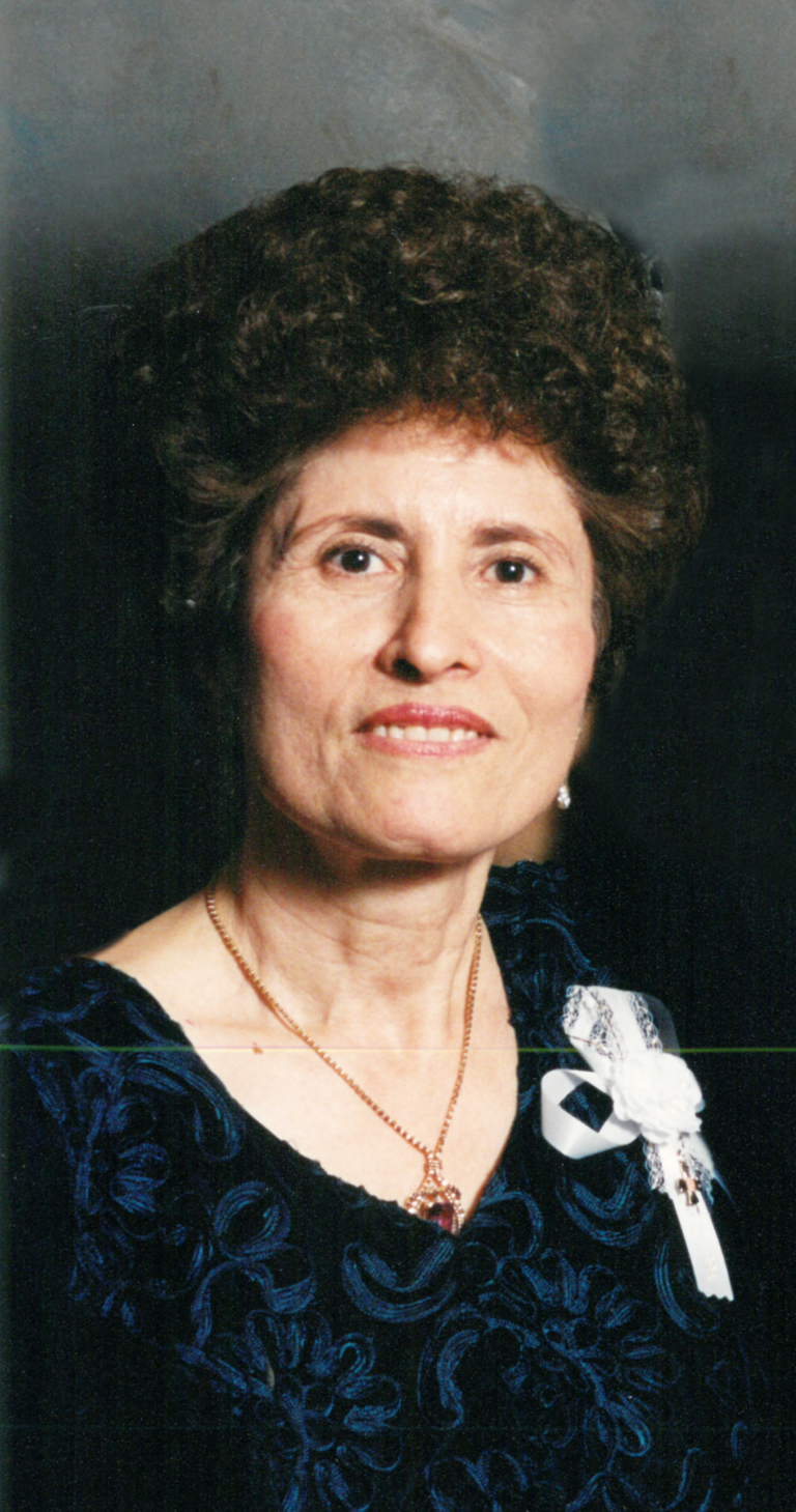 Woman in a blue floral dress smiling.