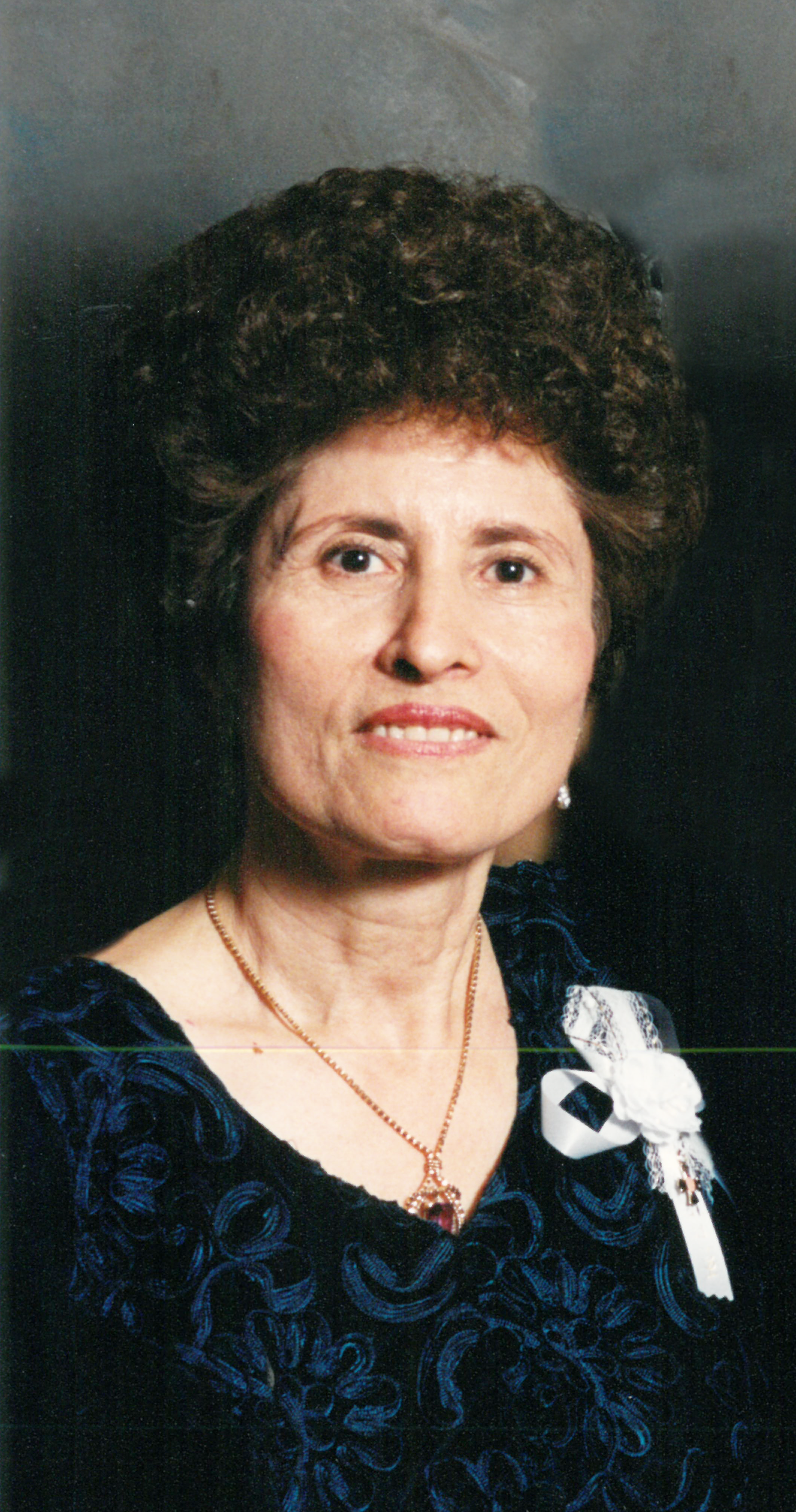 Woman in a blue floral dress smiling.
