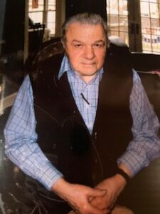 A man in a vest sitting at a table.