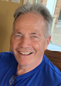 A man in a blue shirt smiles for the camera.