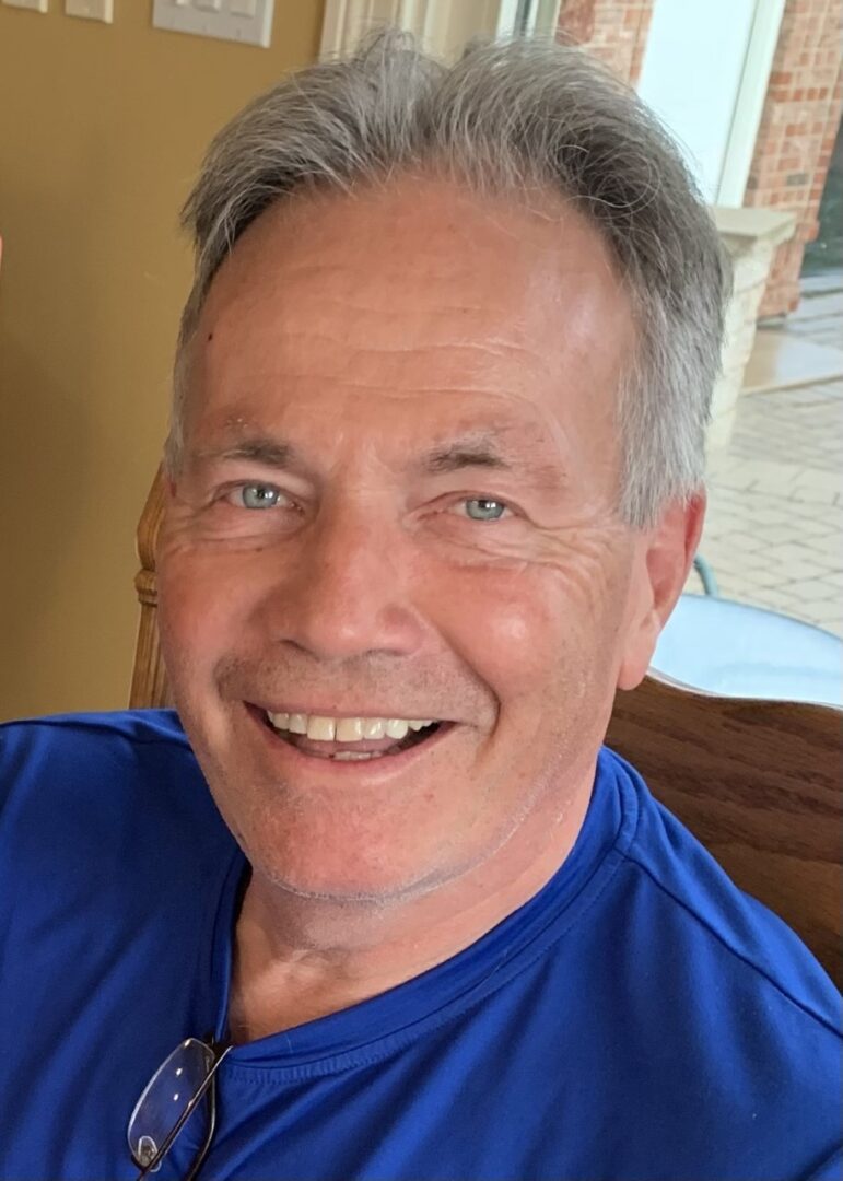 A man in a blue shirt smiles for the camera.