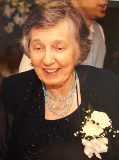 An older woman in a black dress with a bouquet of flowers.
