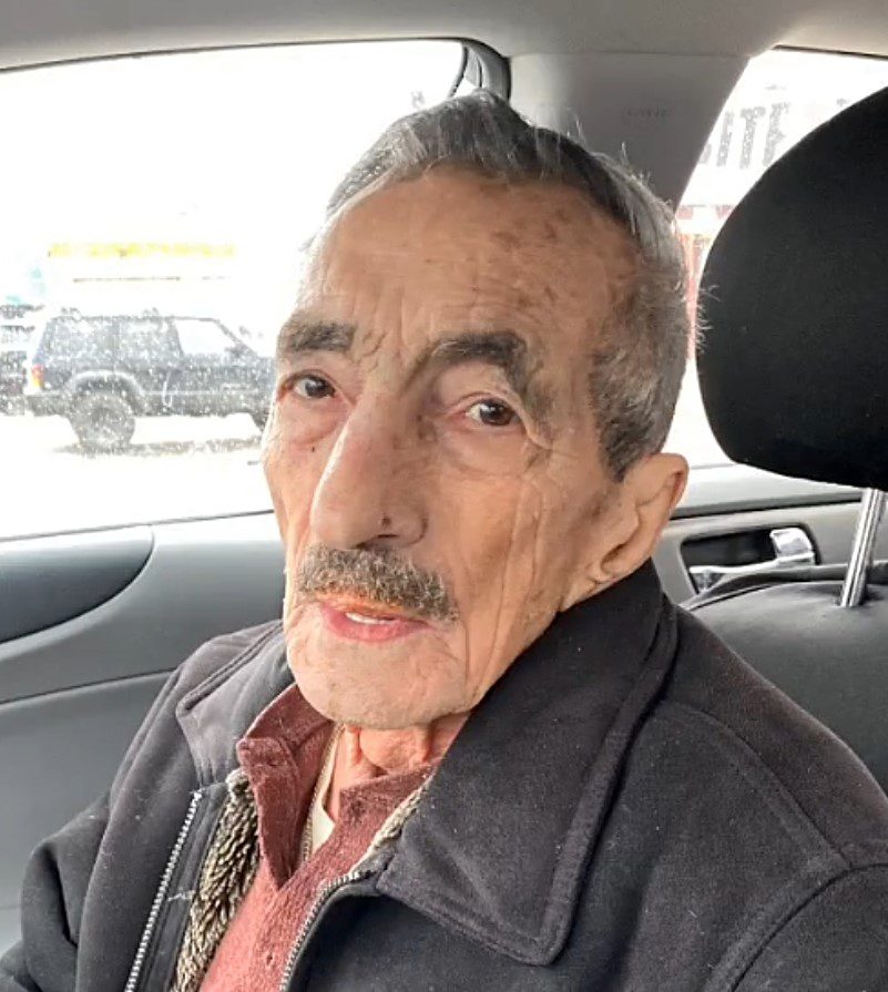An old man sitting in the back seat of a car.