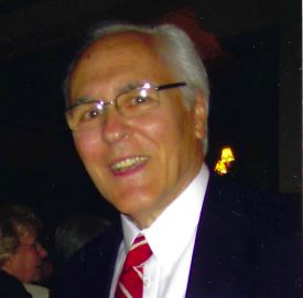 Lilly Kretsos, a man in a suit and tie, smiles for the camera.