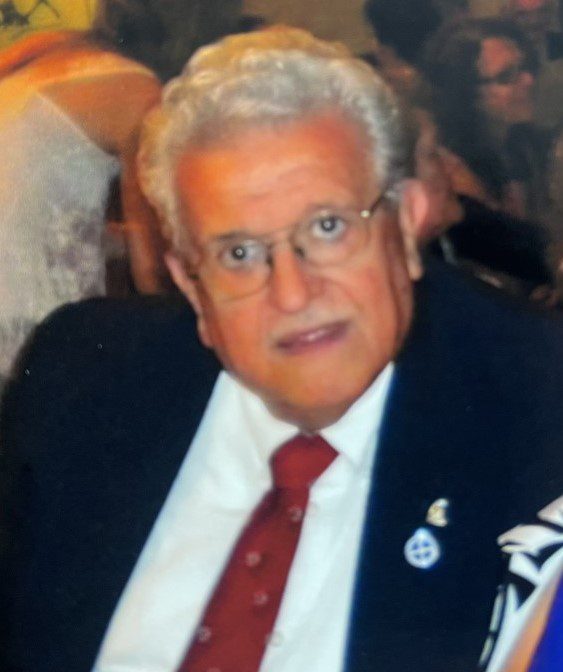 Lilly Kretsos, a man in a suit and tie, sitting at a table.