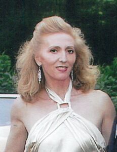 Lilly Kretsos, a woman in a dress, standing next to a car.