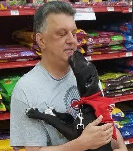 Lilly Kretsos, a man, affectionately kisses a dog in a pet store.