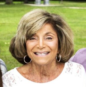 Three older women smiling for the camera in a park.